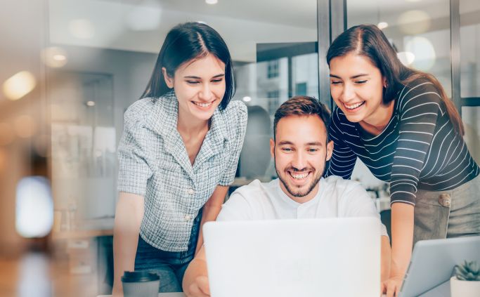 Drie collega's kijken samen naar een laptop.